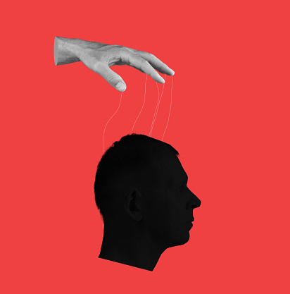 Control over human mind. Hand with strings and head on red background. Manipulation of person consciousness, thoughts, opinion. High quality photo