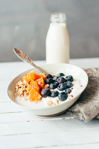 Granola with blueberries and tangerine in a bowl standing on a table