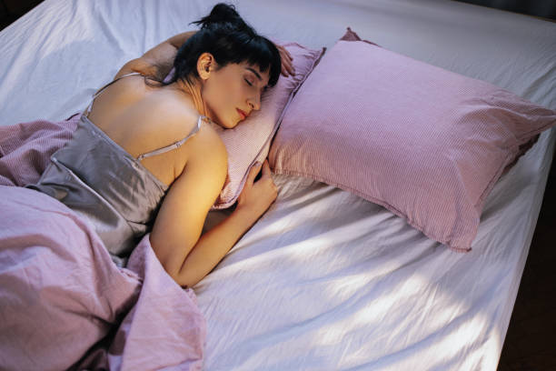 Young Caucasian woman comfortably lying in bed in her pyjamas, sleeping.