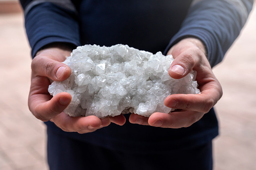 The person is holding some colemanite mineral (bor, boron, borax, ulexite). It is a borate mineral found in evaporite deposits of alkaline lacustrine environments.