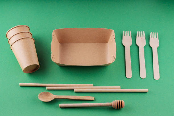 istock Eco-friendly tableware, paper disposable cup and wooden cutlery on a green background. Environmentally friendly disposable tableware, bamboo straws and forks. Plastic free concept 1402350877