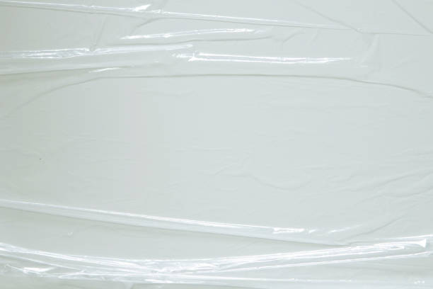 istock Wrinkled plastic wrap on white color background. Crumpled transparent plastic cellophane. Reflecting light and shadow on creases and folds in plastic surface. Texture overlay effect template 1402351159
