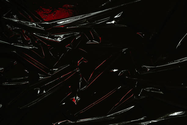 istock Transparent plastic wrap on black background. Crumpled wrinkled plastic cellophane. Reflecting red color light and shadow on creases and folds in plastic surface. Texture overlay effect template 1402351258