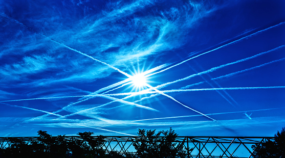 Environmental impact of aviation. Aircraft contrails over blue sky.