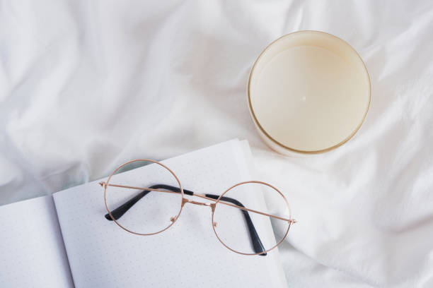 istock eye glasses, aroma candle and open blank notepad on white crumpled cloth 1402356382