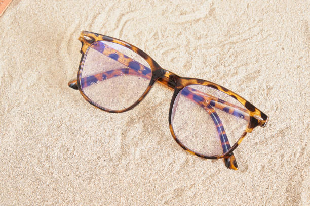 istock stylish eye glasses with spotted plastic frames on the sand, copy space 1402356604