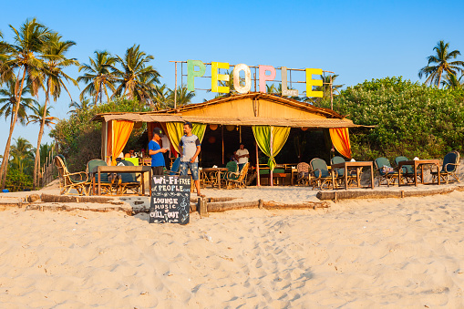 GOA, INDIA - DECEMBER 09, 2016: People beach restaurant shack and sunbeds on Arambol beach in north Goa, India.
