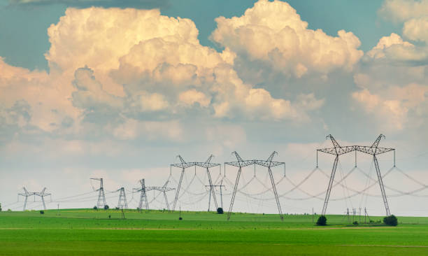 Electric power lines on the countryside field with big clouds on the background. stock photo