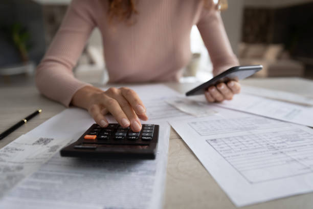 istock Close up woman calculating bills, using calculator and smartphone 1402361670