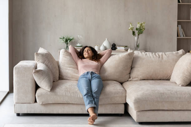istock Smiling barefoot woman resting on comfortable couch at home 1402361689