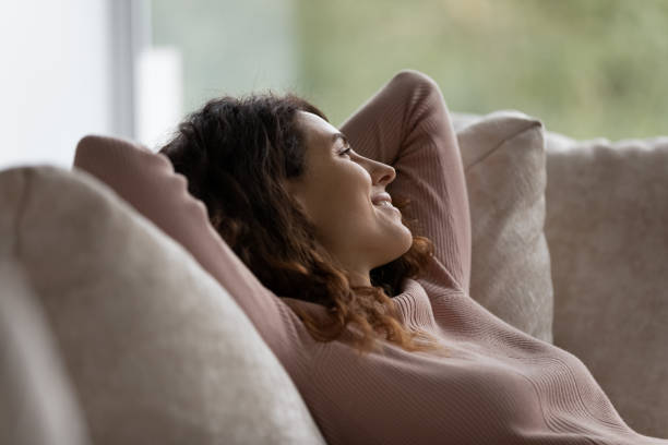 istock Close up smiling dreamy beautiful woman relaxing on comfortable couch 1402361690