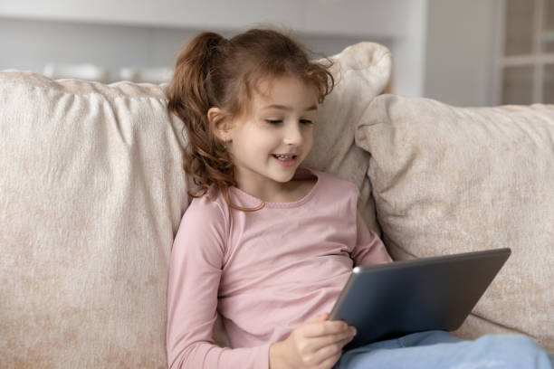 istock Close up adorable cute girl kid using tablet at home 1402362315