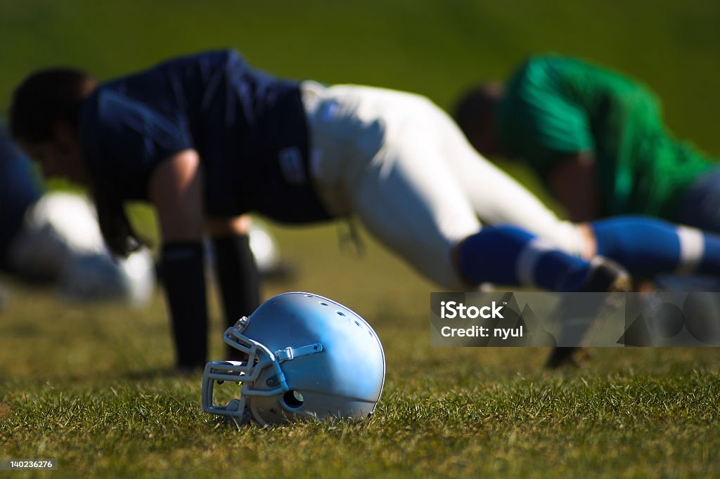 American football player does push up on grass beside helmet Football players are doing training. American Football - Sport Stock Photo