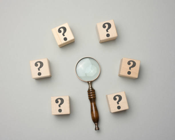 istock Wooden magnifier and cubes with question marks on gray background 1402362837