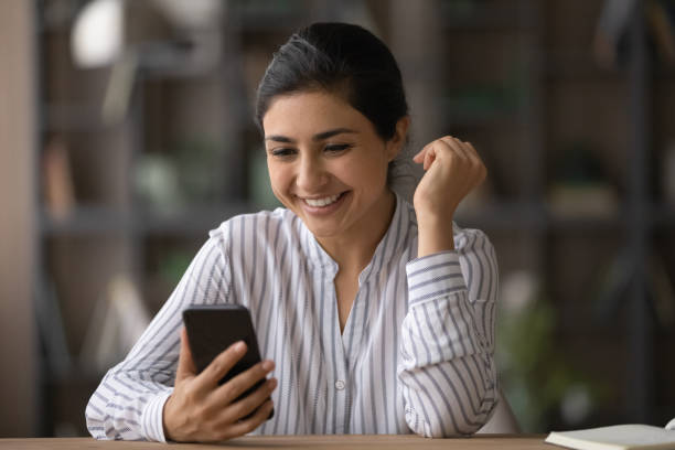 giovane donna indiana felice che usa il cellulare. - women dependency business time foto e immagini stock