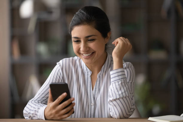 счастливая молодая индийская женщина, использующая мобильный телефон. - women dependency business time стоковые фото и изображения