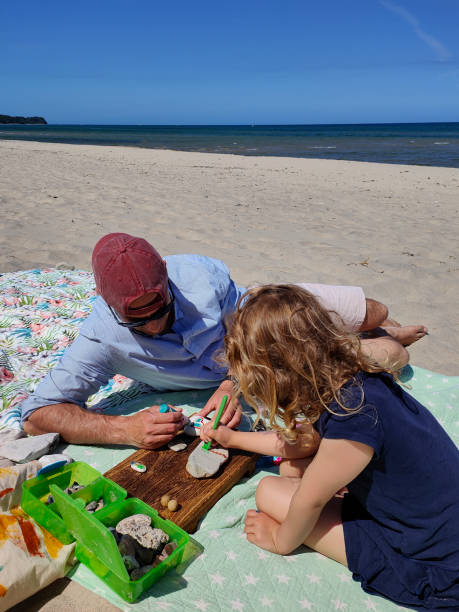 istock Fatherhood: painting rocks on beach 1402365163