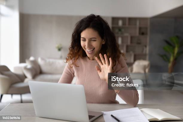 Smiling Friendly Hispanic Businesswoman Waving Hand At Laptop Webcam Stock Photo - Download Image Now