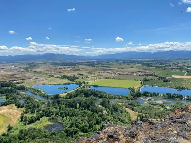 Aerial View of the lush green Rogue Valley in Southern Oregon from atop Table Rock Plateau with different shades of green and a pond, clouds in the sky