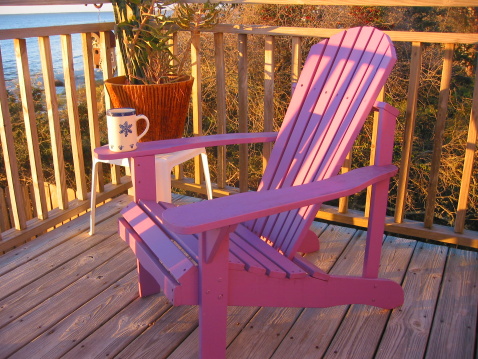 Purple wooden beach chair at sunrise with coffee mug on arm