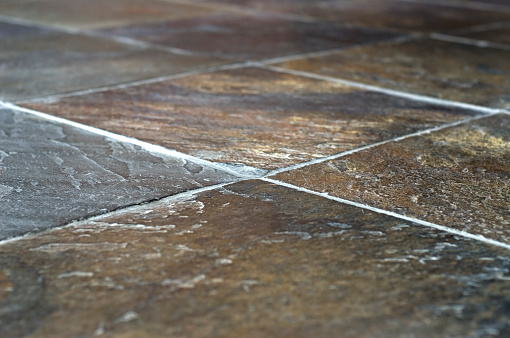 Closeup image of slate tile flooring with brown tones and shallow depth of field.