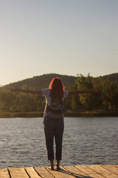 istock Young woman with outstretched hands at sunset 1402373475