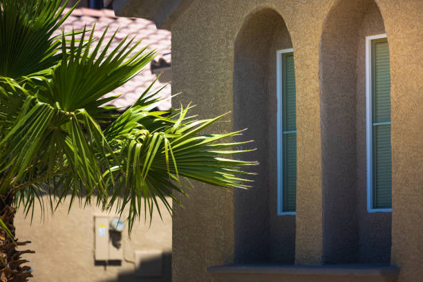 A close up crop of a residential home with green trees/plant life in the foreground.