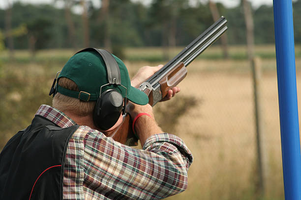 arcilla un hombre sosteniendo un tirador de pistola en su hombro - target shooting fotografías e imágenes de stock
