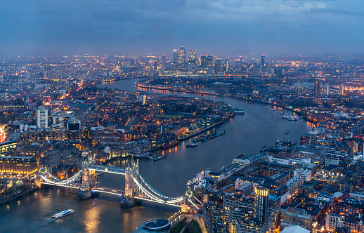 Aerial view of Tower Bridge Over Thames River amidst cityscape at night, London, UK