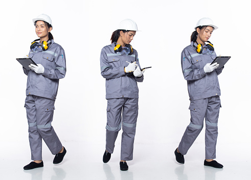 Full length 20s young Asian Woman contractor engineer, working hard thinking, wear hardhat uniform safety gear. Smile Industry female hold blueprint coffee cup over white background isolated