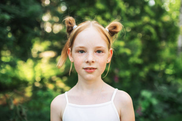 Portrait of redhead girl with freckles on summer blurred background. Cheerful and happy childhood stock photo