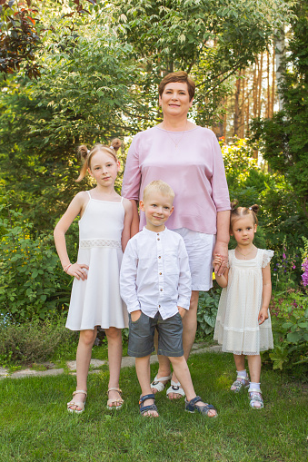 Family portrait. Woman smile. Two sisters and brother outdoors. Grandparent and children together. Summer vacation. Outdoor recreation. Leisure activity. Age. Grandmother and grandchildren