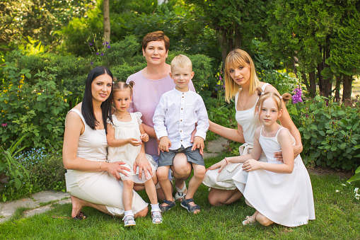 Portrait of multi-generation family standing together outside by the pool at home on a sunny day and smiling at the camera. Happy extended caucasian family bonding in their backpack