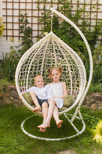 Blonde boy and girl on wicker lounge chair. Childhood. Summer vacation. Outdoor recreation. Rest. Children portrait together on sunbed. Leisure activity. Brother and sister. Friendship. Relationship