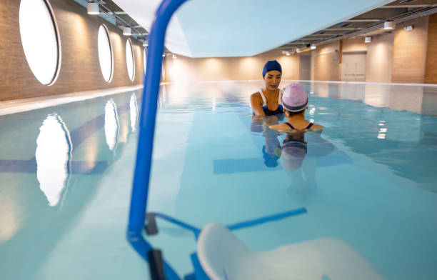 istock Therapist helping a woman doing her physical therapy in a swimming pool 1402396889