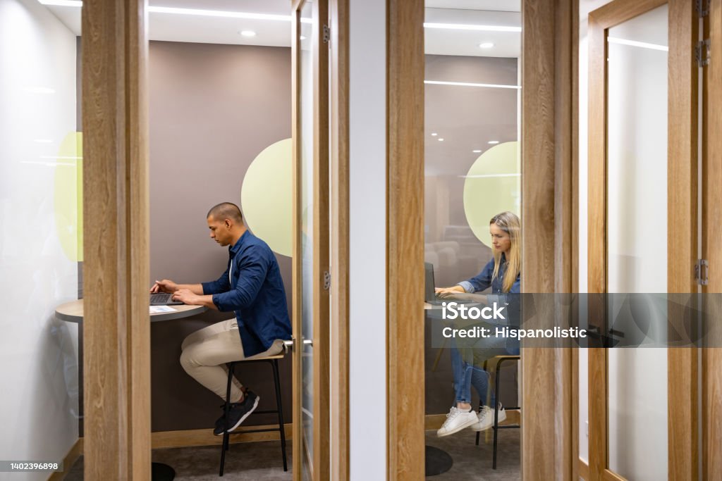 Business people working in private cubicles at a coworking office Latin American business people working in private cubicles at a coworking office Office Stock Photo