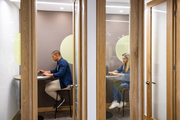 Business people working in private cubicles at a coworking office stock photo