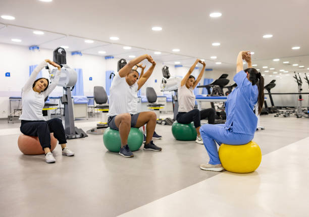 groupe de patients suivant les instructions de leur physiothérapeute - centre de désintoxication photos et images de collection