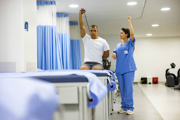 Latin American man doing physical therapy exercises with the guidance of his therapist and using a resistance band