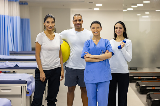 Female physical therapist smiling with a group of patients at a rehabilitation center