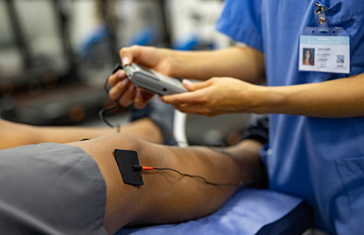 Close-up on a man in physiotherapy getting electrical stimulation therapy on his knee