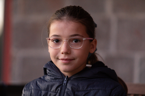 Cute 11 years-old girl with glasses looking at camera