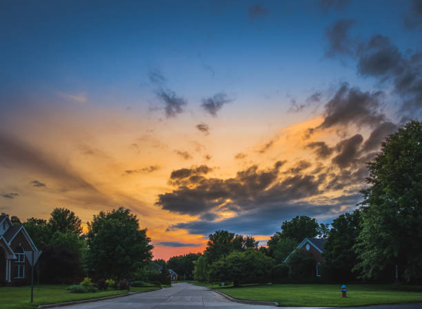 Beautiful dramatic sky over suburban Midwestern neighborhood at sunset in summer Beautiful dramatic sky over suburban Midwestern neighborhood at sunset in summer suburb house street residential district stock pictures, royalty-free photos & images