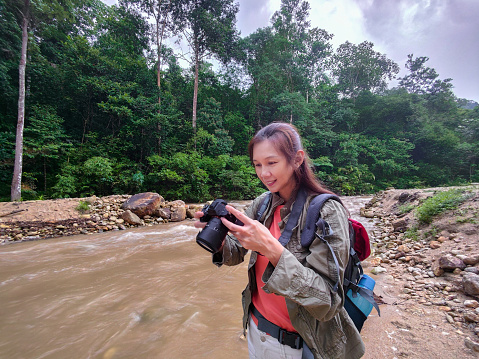 female landscape photographer checking on the photos she captured in forest area