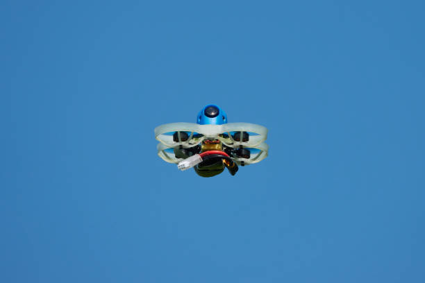 istock Small Drone blue also race quad, with protective gondola in white with a blue sky. photographed from below. Germany. 1402415391
