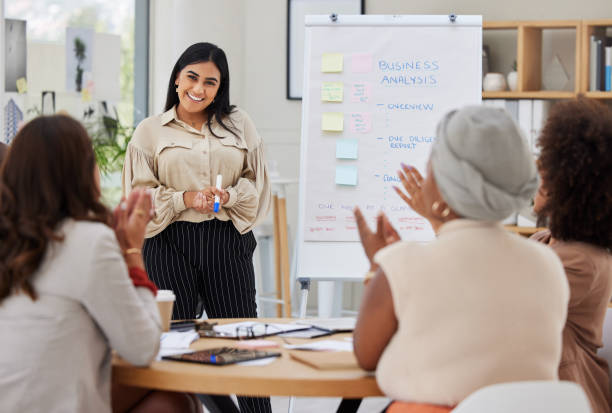 istock Ambitious indian business woman using a whiteboard for staff training in an office workshop. Ethnic professional standing and teaching team of colleagues. Sharing ideas and planning marketing strategy 1402421036