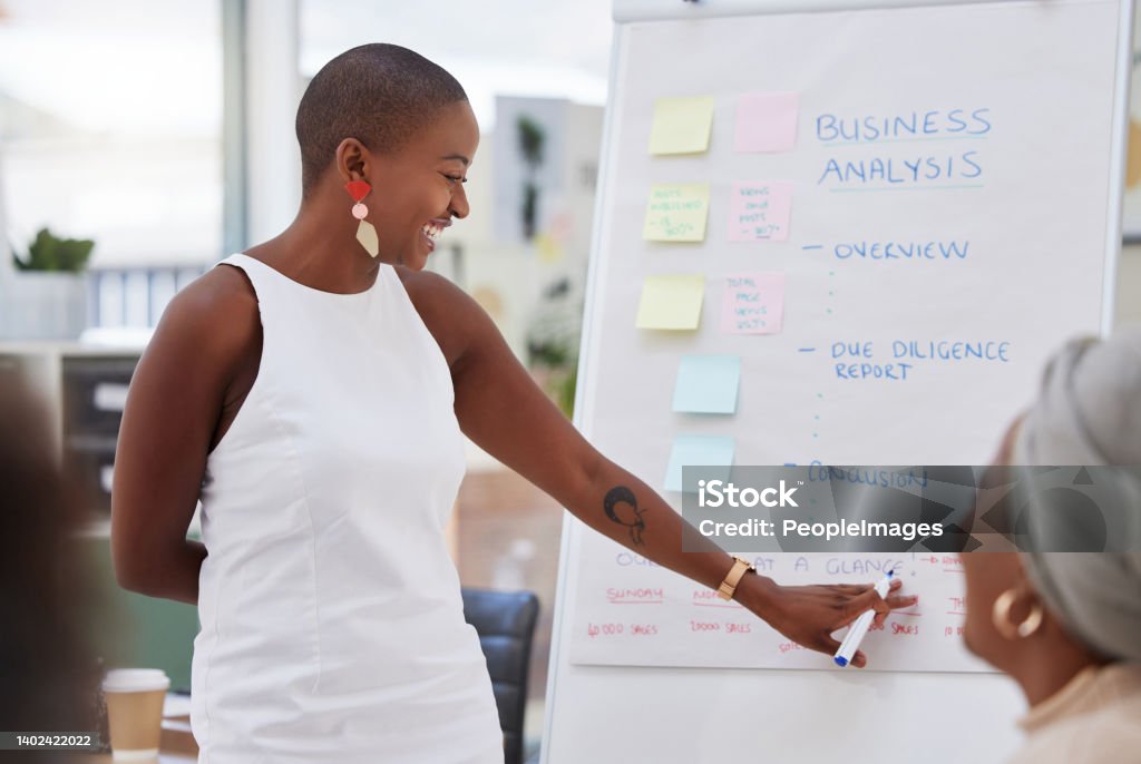 Ambitious african american businesswoman using whiteboard to train staff in office workshop. Black professional standing and teaching team of colleagues. Sharing idea and planning marketing strategy Entrepreneur Stock Photo