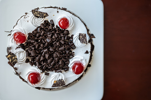 Chocolate cake with whipping cream,  cherry and chocolate for garnishing