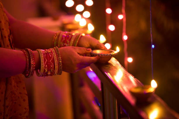 nahaufnahme von frau beleuchtung diya auf geländer - diwali lights stock-fotos und bilder