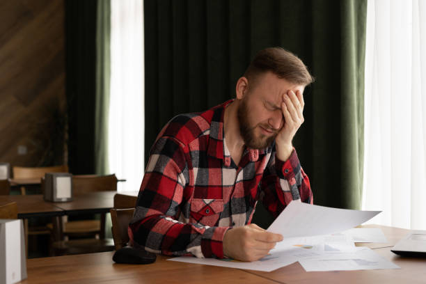 istock frustrated young man reading documents and using laptop in cafe, money problem, debt notification, bad financial report, money problem, unsuccessful exam or test results 1402426717